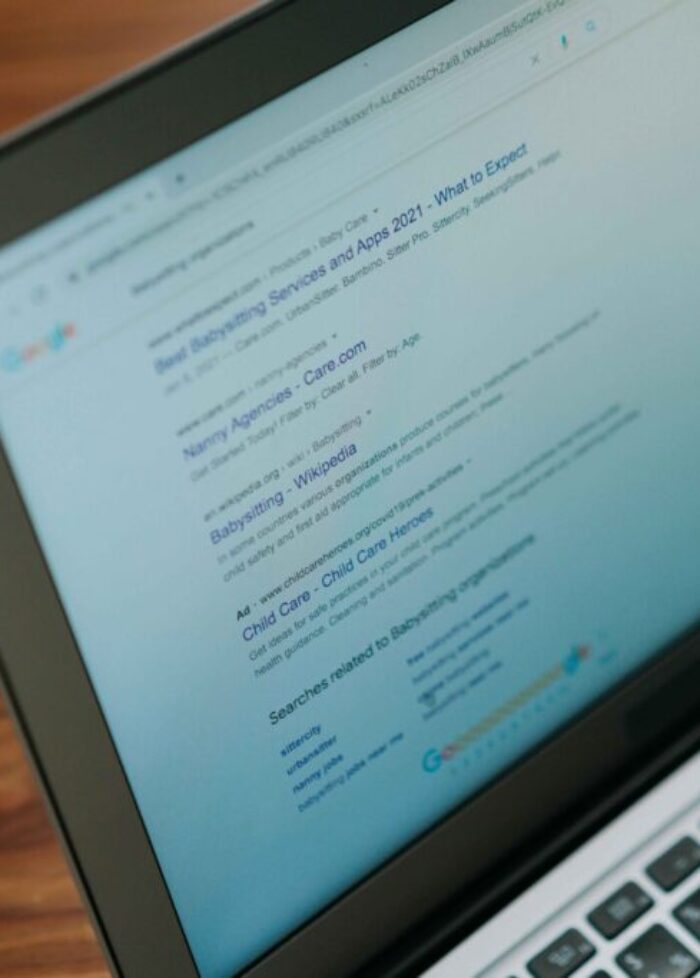 Laptop displaying Google search engine results for babysitting services and apps, representing SEO research and digital marketing analysis.